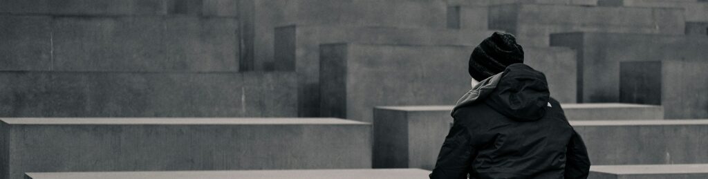 grayscale photo of woman sitting on concrete block